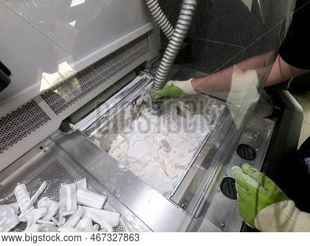 Male Worker Taking Out Models From White Polyamide Powder In Working Chamber Of 3d Printer, Cleaning