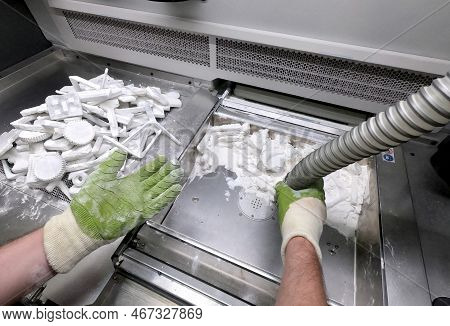 Male Worker Taking Out Models From White Polyamide Powder In Working Chamber Of 3d Printer, Cleaning
