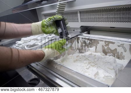 Male Worker Taking Out Models From White Polyamide Powder In Working Chamber Of 3d Printer, Cleaning
