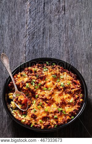 Cajun Beef Cornbread Casserole Topped With Melted Red Cheddar Cheese And Scalions In Baking Dish On 