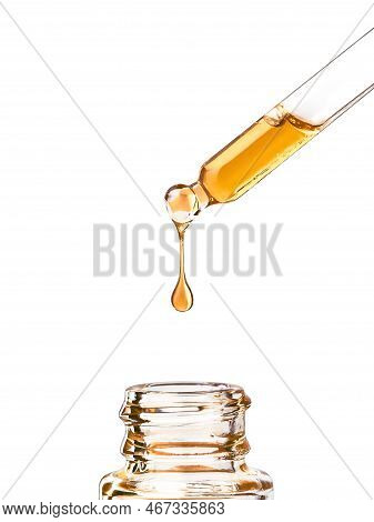Cosmetic Pipette With Yellow Oily Drop Close Up, Isolated On White Background. Beauty Drop Of Luxuri