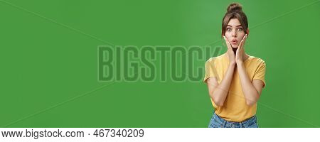 Silly Cute And Tender Young Female Model With Cleacn Skin Folding Lips, Pressing Hands To Cheeks And