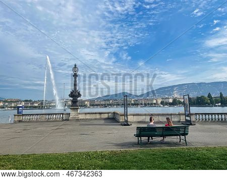 Geneva, Switzerland - September 14 2021: Two Woman Are Sitting Relaxed On A Park Bench With Panorami