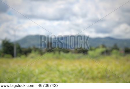 Defocused Or Unfocused Or Blurred Of Empty Land Overgrown With Weeds At The Crossroads, With Mountai