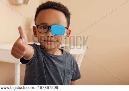 African American Boy With Eye Patch On Glasses Showing Thumb Up In Room, Space For Text. Strabismus 