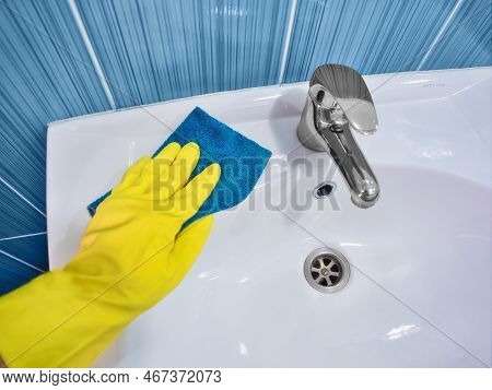 Hand In Yellow Rubber Glove With Rag Wipes White Sink. Cleaning And Disinfection With Cleaning Agent