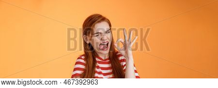 Sassy Asserive Relaxed Redhead Woman Assuring Everything Under Control, Make Deal, Wink Show Tongue 
