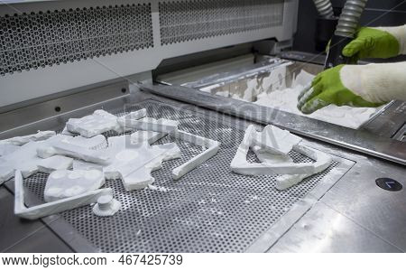 Male Worker Taking Out Models From White Polyamide Powder In Working Chamber Of 3d Printer, Cleaning