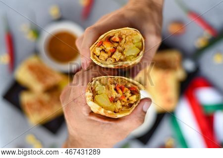 Hands Holding Vegetarian Mexican Burritos With Potato, Tofu,rice Served With Sauce Brracha