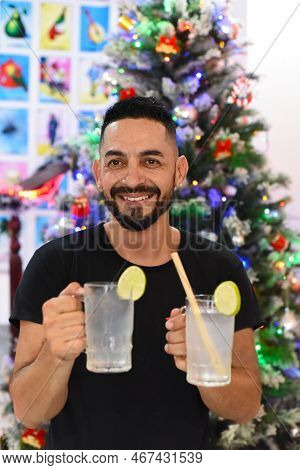 Mexican Man Holding Mexican Drinks Horchata Water And Lemon Juice Against Christmas Tree