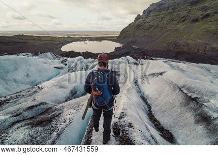Mountaineer With Backpack On Snowy Slope Scenic Photography. Picture Of Person With Mountain Lake On