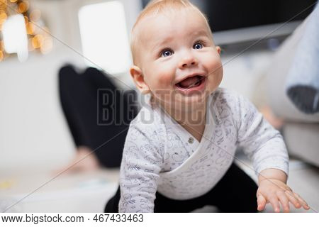 Cute Infant Baby Boy Playing, Crawling And Standing Up By Living Room Sofa At Home. Baby Playing At 