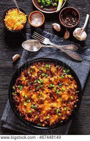 Cajun Beef Cornbread Casserole Topped With Melted Red Cheddar Cheese And Scalions In Baking Dish On 