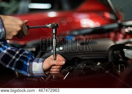 Female Auto Mechanic Unscrewing A Nut To Replace A Car Spark Plug.