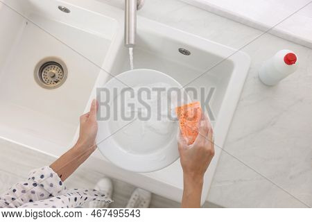 Woman Washing Plate Above Sink In Modern Kitchen, Top View