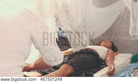 Male Masseur Massages The Legs In A Beautiful White Ornamrental Tent.