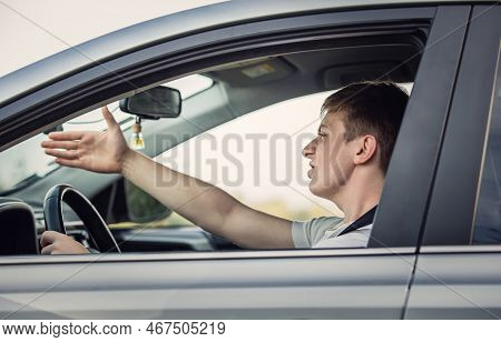Furious Driver Gesturing With His Hand To The Traffic Jam Ahead His Car. Aggressive Guy Unsafe Drivi