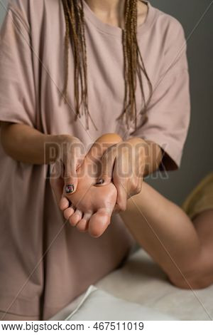 Close-up Reflexological Foot Massage. Professional Therapist Who Massages The Legs And Feet Of A Wom