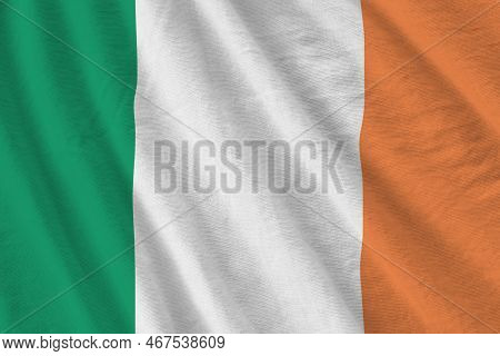 Ireland Flag With Big Folds Waving Close Up Under The Studio Light Indoors. The Official Symbols And