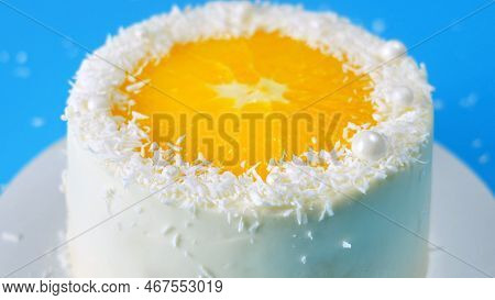 Cake With Orange And Coconut Shavings Spinning On A Blue Background.