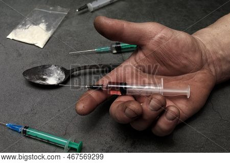 Syringe For Injection In A Man's Hand. The Hand Holds The Syringe. The Concept Of Drug Addiction, Po