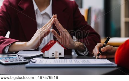 Discussion With A Real Estate Agent, House Model With Agent And Customer Discussing For The Contract