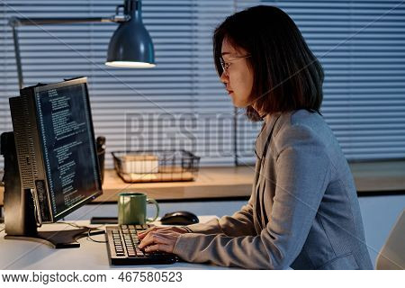 Asian It Specialist Typing Codes For Program On Computer Working At Her Workplace Till Late Evening