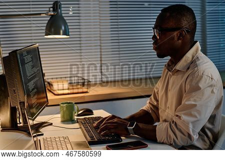 Serious African American Programmer Typing Codes On Keyboard For New Computer Program During Work In