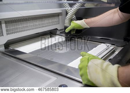 A Male Worker Cleans The Surface Of An Industrial 3d Printer From White Powder With A Vacuum Cleaner