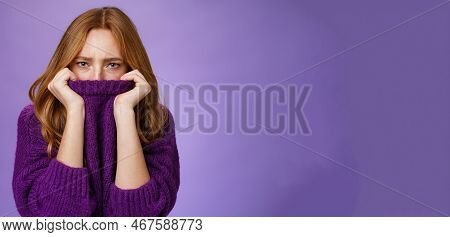 Gloomy Upset Redhead Girlfriend Pulling Collar Of Purple Sweater On Nose, Frowning And Squinting Off