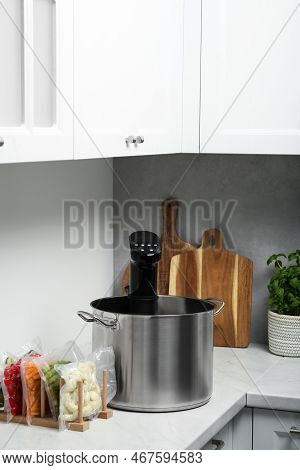 Pot With Sous Vide Cooker And Vacuum Packed Food Products In Kitchen. Thermal Immersion Circulator