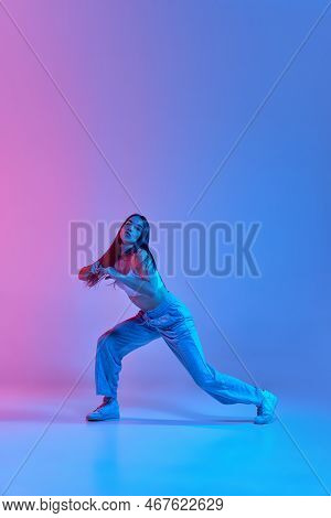 Young Stylish Girl Dancing Hip-hop Isolated Over Gradient Pink Blue Background In Neon Light. Dynami