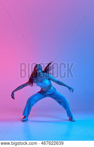Young Stylish Girl Dancing Isolated Over Gradient Pink Blue Background In Neon Light. Contemporary D
