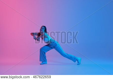 Young Active Girl Dancing Contemporary Dance Over Gradient Pink Blue Background In Neon Light