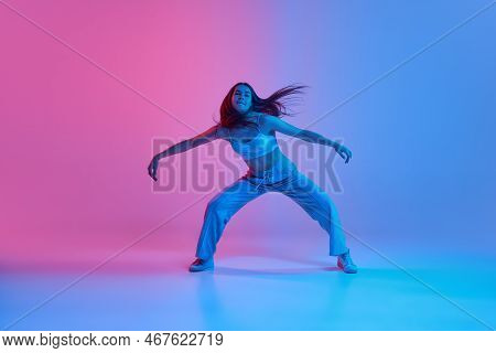Young Girl Dancing Hip-hop Over Gradient Pink Blue Background In Neon Light. Contemp