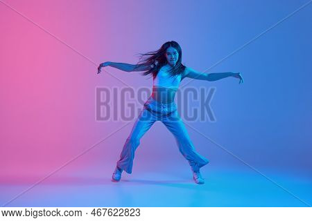 Young Stylish Girl Dancing Over Gradient Pink Blue Background In Neon Light. Rhythmic Dance