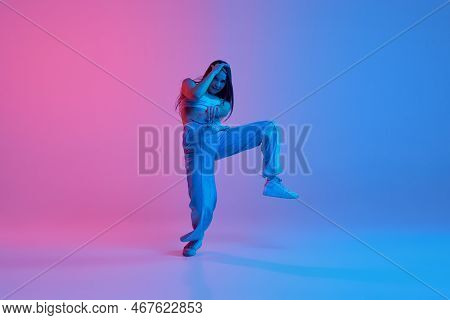 Young Stylish Girl Dancing Over Gradient Pink Blue Background In Neon Light. Expressive Dance