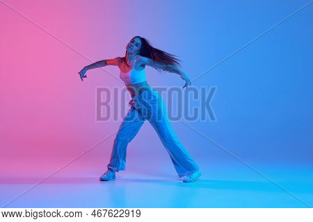 Young Stylish Girl Dancing Over Gradient Pink Blue Background In Neon Light. Dance Of Freedom