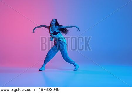 Young Stylish Girl Dancing Over Gradient Pink Blue Background In Neon Light. Flexible Movements