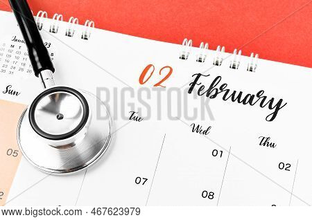 Stethoscope Medical And February 2023 Desk Calendar On The Red Background, Schedule To Check Up Heal