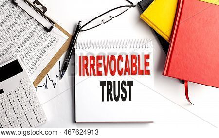 Irrevocable Trust Text On Notebook With Clipboard And Calculator On A White Background
