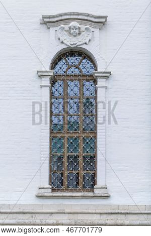 Arched Window With Onament And Bars In A White Brick Building. Fortresses And Historic Houses. Verti