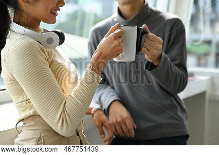 Cropped Shot Of Tea Young Employee Having Conversation During Break While Standing In Near Office Wi