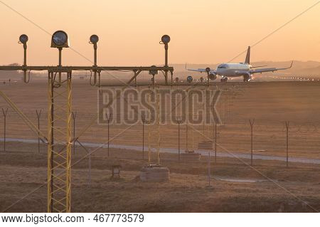 Poland, Krakow, Balice Airport, Runway Lights Andcommercial Aircraft Taxiing At Sunset,