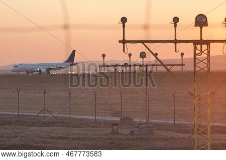 Poland, Krakow, Balice Airport, Runway Lights Andcommercial Aircraft Taxiing At Sunset,