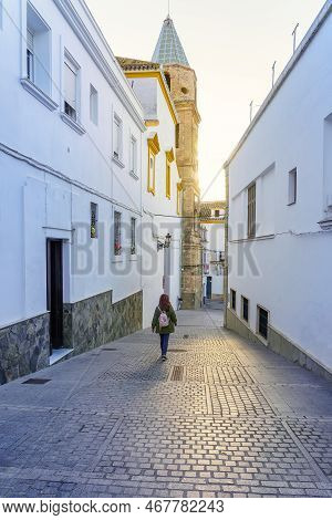 Tourist Woman Strolling Through The Narrow Streets At Sunset On A Sunny Day, Medina Sidonia, Cadiz.