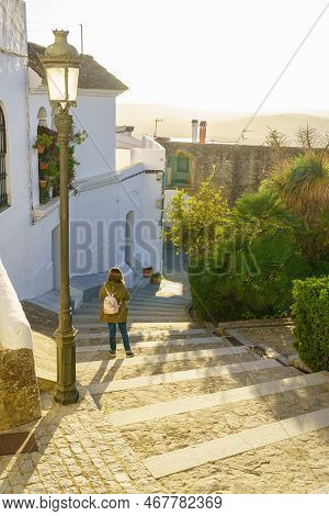 Tourist Woman Strolling Through A Narrow Alley At Sunset On A Sunny Day In The City Of Medina Sidoni