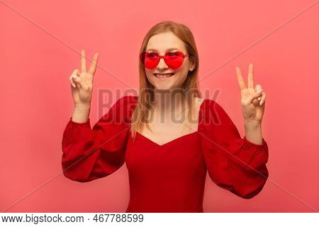 Happy Smiling Girl Showing Peace Gesture V Sign With Four Fingers And Looking Aside Isolated On Colo