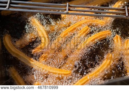 Process Of Cooking Homemade Crunchy Yellow Churros In Boiling Oil At Summer Outdoor Food Market - Cl
