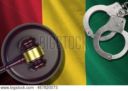 Guinea Flag With Judge Mallet And Handcuffs In Dark Room. Concept Of Criminal And Punishment, Backgr
